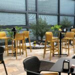 Net Tall Bar Stools in Mustard with Bar Leaners Outdoors at Cafe